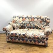 An early 20thc two seat sofa, the padded back, arms and seat with additional cushions, all