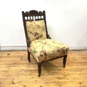 A late Victorian easy chair, the carved top rail incorporating a stylised foliate design, above an