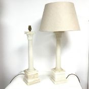 A pair of alabaster Corinthian column style table lamps, the capitals over plain columns, on a