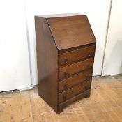 A 1920s small bureau, the rectangular fall front enclosing pigeonholes and a writing surface,