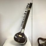 An Indian sitar with inlaid bone decoration and carving (a/f) (l.130cm x 34cm)