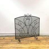 A wrought iron and mesh spark guard, the arched frame incorporating scrolling details on inverted