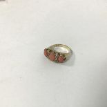 A 9ct gold dress ring mounted oval polished coral flanked by a coral oval cut stone to each shoulder