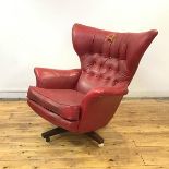 An early 1970s wing armchair, the flared and buttoned back and cushioned seat upholstered in red