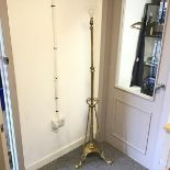 A brass floor lamp, the cylindrical stem supported by three curved supports terminating in a