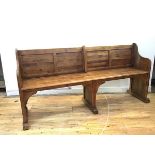 A pine pew style bench by Arhaus, the panel back and slatted seat within shaped arms, on square