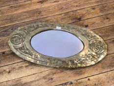 A Glasgow School style Arts & Crafts oval wall mirror, the brass frame embossed with Celtic motifs