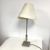 A polished steel table lamp with circular stem above a square plinth, on square base with bracket