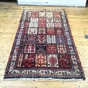 A hand woven tile pattern carpet, each tile decorated with stylised patterns in madder, ivory and