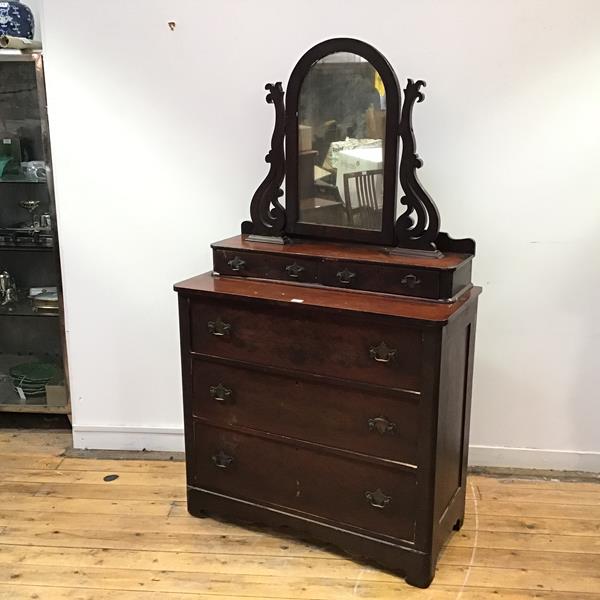A late 19thc dressing chest, possibly American, the raised back incorporating an arched mirror plate