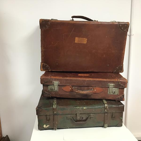 A group of vintage travelling cases including two in brown leather, the third in canvas with a
