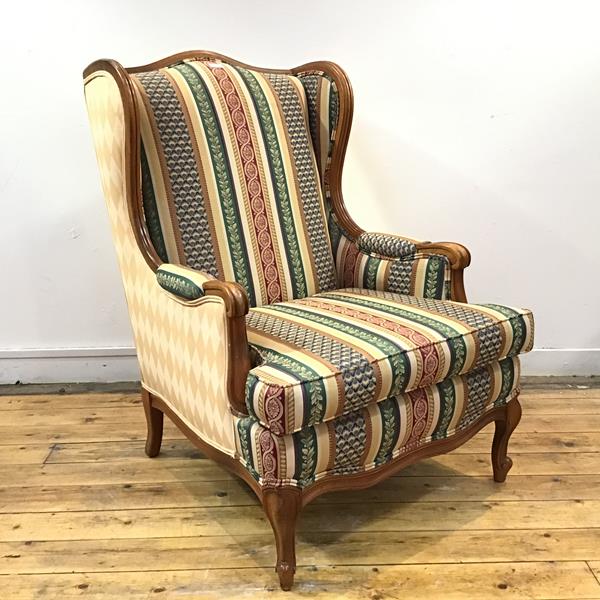 A modern wing armchair, the moulded fruitwood frame enclosing a striped fabric back and seat, raised