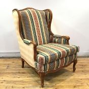 A modern wing armchair, the moulded fruitwood frame enclosing a striped fabric back and seat, raised