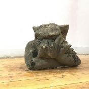 A composition stone gargoyle, modelled in repose, with claw hand to cheek and arms folded