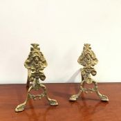 A pair of brass fire dogs, each with cartouche decoration and central mask (h.30cm)