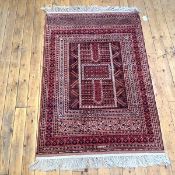 A finely-knotted Turkoman rug, the madder field with central mihrab design outlined in ivory, within