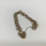 A 9ct gold chainlink bracelet, of fancy double hoop links, suspending a heart padlock clasp, with