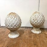 A pair of cast iron pineapple pier finials, each white-painted, raised on a foliate cast socle base.