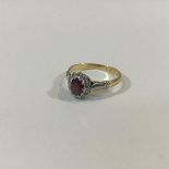 A ruby and diamond cluster ring, the oval-cut ruby claw-set within a band of ten round brilliant cut