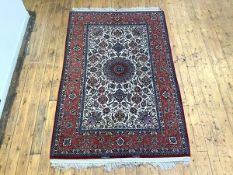 A fine hand-knotted Isfahan carpet, the ivory field with entwined stylised flowers and foliage,