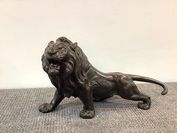 A Japanese bronze model of a lion, Meiji period, cast in ferocious pose with teeth bared, cast
