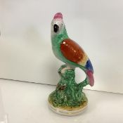 A 19th century Staffordshire model of a parrot, modelled seated on a stump, polychrome painted in