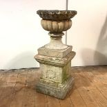A composition bird bath, of campana form, with gadrooned body, raised on an associated plinth,