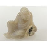 A Chinese celadon jade carving of a seated man, one hand resting on his knee. 4.75cm by 5.5cm