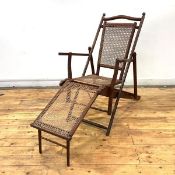 A late 19th century mahogany Campaign lounge chair, the arched top rail above a caned back, seat and