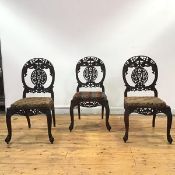 A set of three 19th century Anglo-Indian padouk side chairs, each oval back profusely carved and