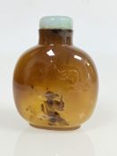 A fine Chinese silhouette agate snuff bottle, carved with a bat above a design of a robed man