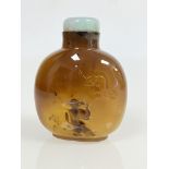 A fine Chinese silhouette agate snuff bottle, carved with a bat above a design of a robed man