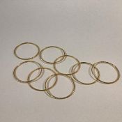 A set of eight Indian yellow metal bangles, each with a chevron pattern, unmarked, probably high