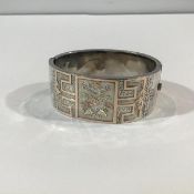 A late Victorian silver (unmarked) and silver-gilt hinged cuff bangle, decorated with an engraved