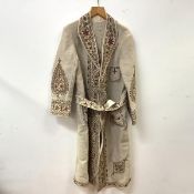 Peshawar, a hand-stitched woollen coat, in a cream wool, the lapels, pockets and borders worked in