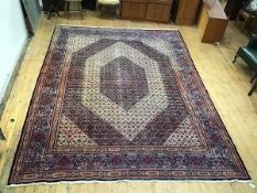 A Persian handwoven carpet, the indigo field with central light blue medallion enclosed by ivory