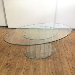 A modern glass occasional table, the oval top on a corresponding base, supported by cylindrical