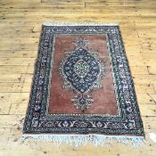 A hand knotted wool North West Persian rug, the fawn field enclosing a floral medallion within