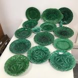 An assortment of green majolica plates with foliate decoration, some marked Wedgwood, two marked