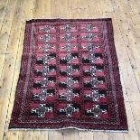 A hand knotted wool rug of Turkoman design, the madder field with a grid design enclosing ivory