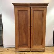 A Victorian pine wardrobe, reduced in width, the projecting cornice above a pair of panelled