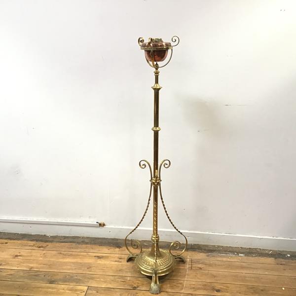 An Edwardian brass floor standing oil lamp with copper burner, the stem with three ribboned supports