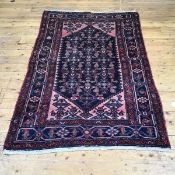 A hand knotted wool Hamadan rug, the indigo field with geometric motifs enclosed by salmon pink