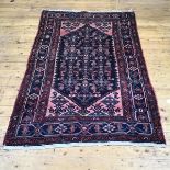 A hand knotted wool Hamadan rug, the indigo field with geometric motifs enclosed by salmon pink