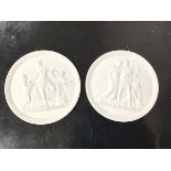 A pair of Royal Copenhagen white basalt plaques, each depicting a classical scene within a foliate