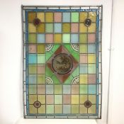 A stained leaded glass panel, c.1900 of chequerboard design with a central circular panel