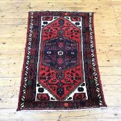 A Hamadan rug, the tomato red field enclosing an indigo medallion within ivory spandrels and