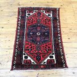 A Hamadan rug, the tomato red field enclosing an indigo medallion within ivory spandrels and