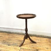 A pedestal wine table, the circular top with moulded scalloped edge and a central tooled leather