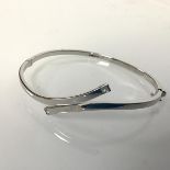 A 9ct white gold stiff hinged bangle, set with two clear stones (6.5cm x 5.5cm) (5.65g)